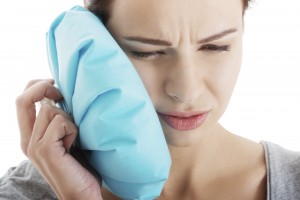 woman with mouth pain holding ice pack up to her face 